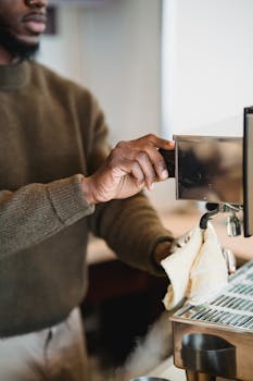 Close-up of a man cleaning a commercial espresso machine in a cafe.