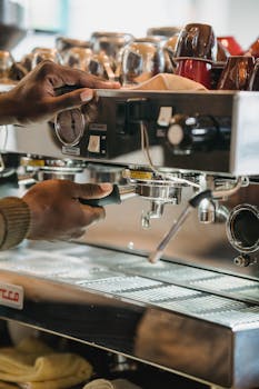 Close-up of hands using an espresso machine in a cafe, making coffee drinks.