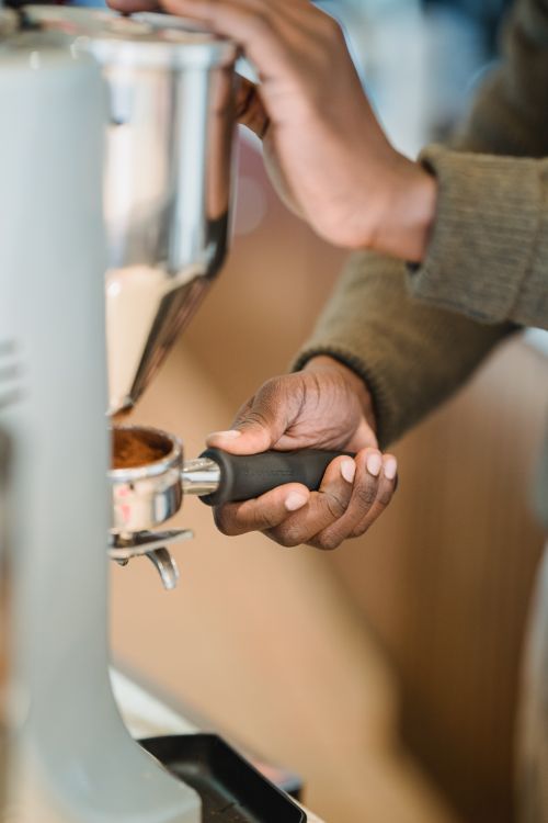 Free Close-up of a barista using a portafilter to make espresso with a coffee machine indoors. Stock Photo