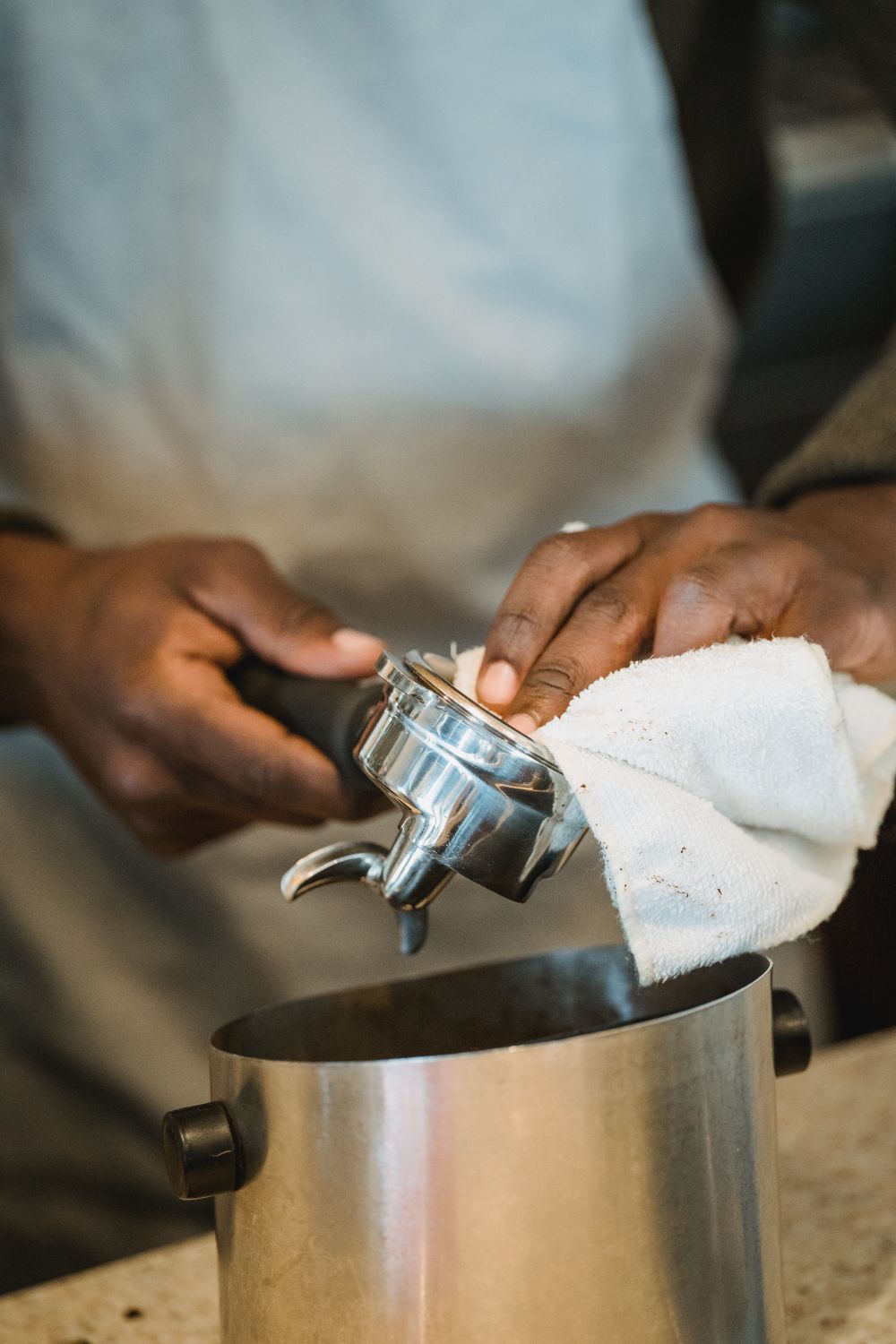 Hands wiping down a bottomless portafilter during maintenance