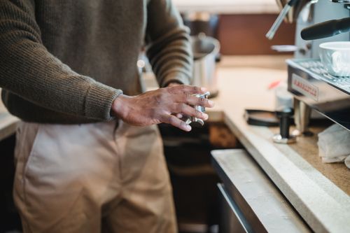 Free Barista hands skillfully working on a coffee machine in a cozy café environment. Stock Photo