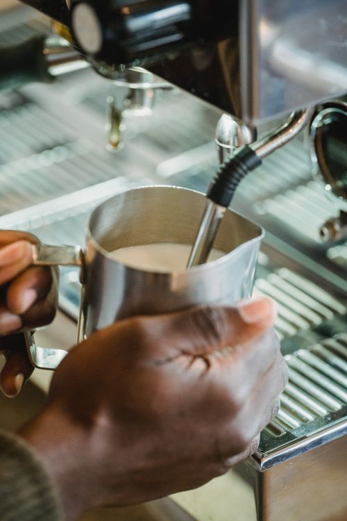 Free Detailed shot of hands using a coffee machine frother to prepare milk, perfect for coffee-related imagery. Stock Photo