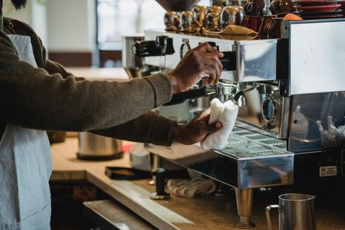 Free A barista cleans the coffee machine at a café, ensuring hygiene and readiness for customers. Stock Photo