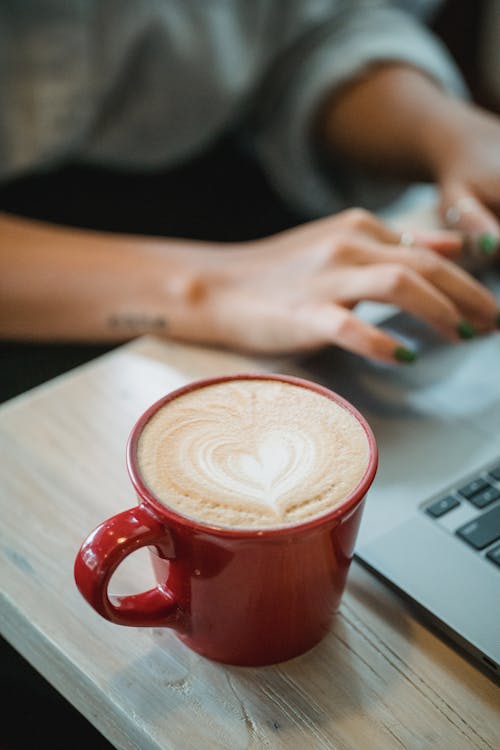 Free Coffee Cup by Person Using Laptop Stock Photo