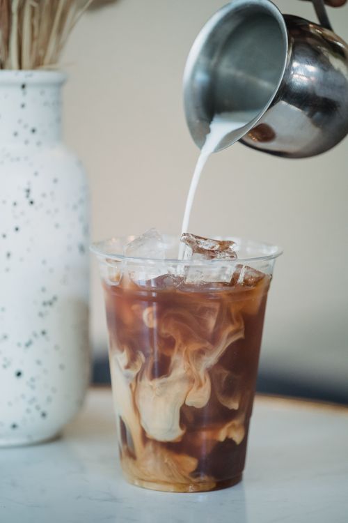 Free Refreshing iced coffee with milk poured in a café environment. Stock Photo