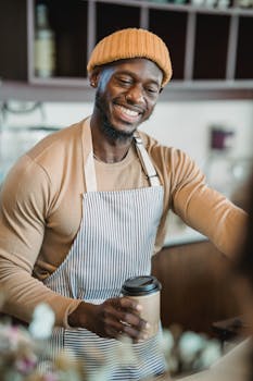 Friendly barista wearing an apron serves a hot coffee with a smile, creating a welcoming atmosphere.