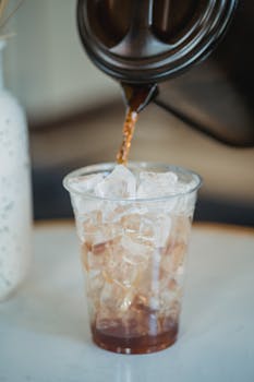 A close-up of a fresh iced coffee being poured into a cup, perfect for a caffeine break.