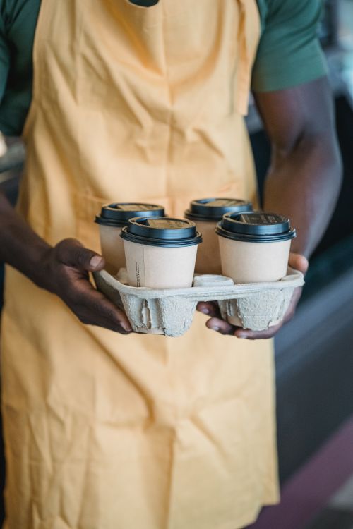Free Close-up of a barista carrying multiple takeaway coffee cups in a cardboard tray. Stock Photo