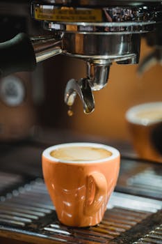 A close-up shot of freshly brewed espresso dripping into a cup from a coffee machine.