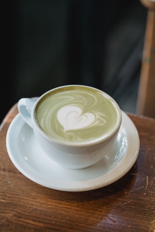 Free Close-up of a heart-shaped latte art on a matcha drink in a white cup on a wooden table. Stock Photo