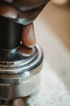 Detailed shot of a hand pressing an espresso tamper, highlighting the coffee-making process.