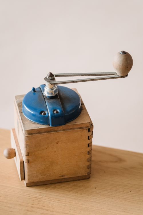 Free Close-up of a vintage wooden coffee grinder with a blue handle on a table. Stock Photo