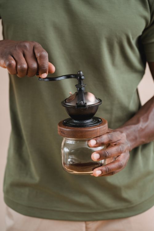 Free Close-up of a man using a manual coffee grinder, focusing on the hands and device. Stock Photo