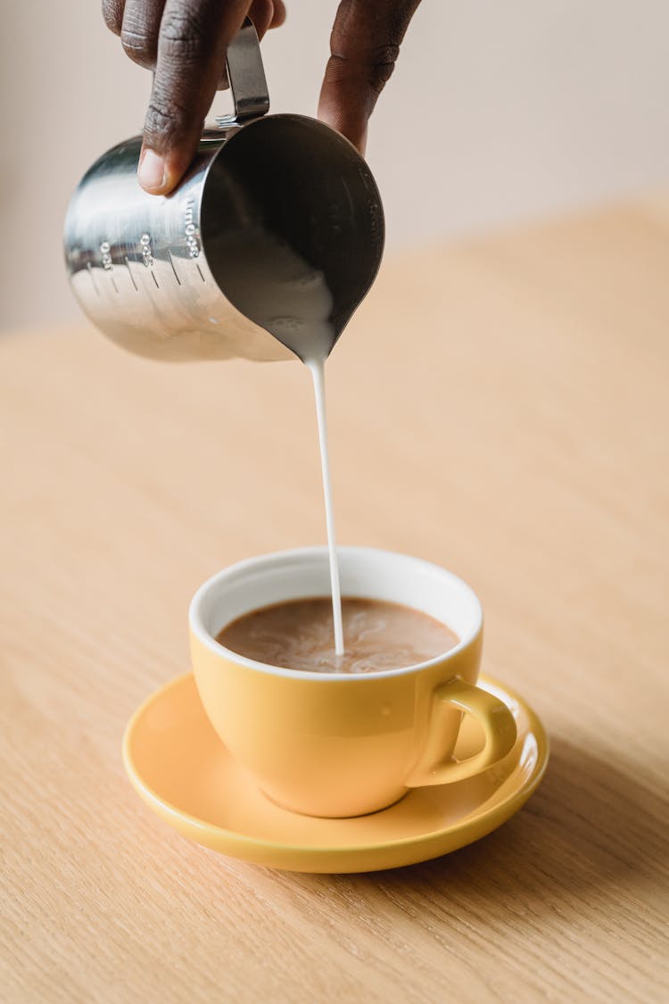 Pouring Milk From Pitcher To Coffee Cup