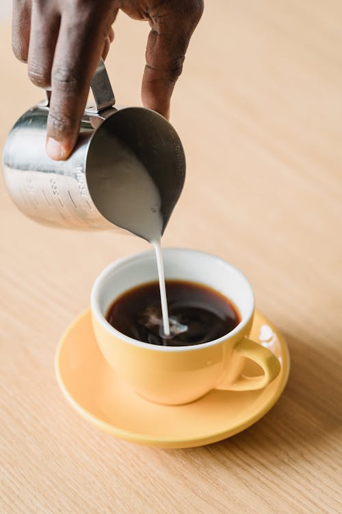 Free Hand Pouring Milk to Coffee Stock Photo