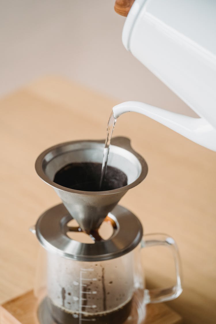 Close Up Of Pouring Water To Sieve With Coffee On Pitcher 