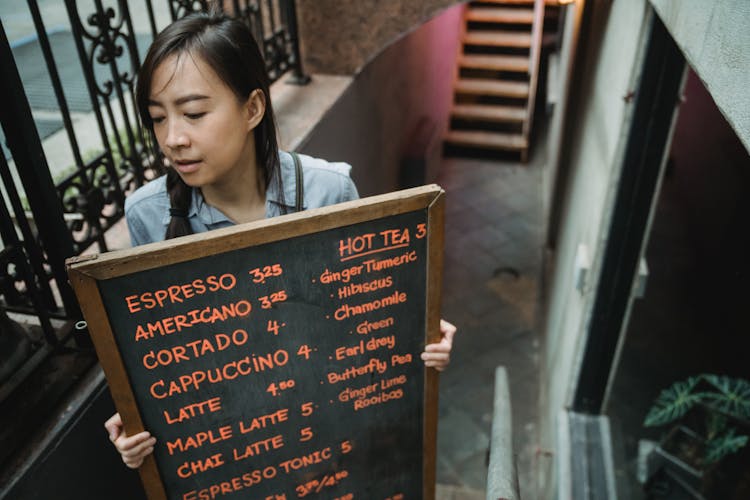 Woman Carrying Blackboard With Cafe Menu