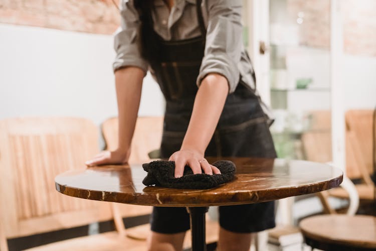 Person Cleaning Table In Cafe