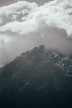 Dramatic view of mountain peaks shrouded in thick clouds, creating a moody atmosphere.