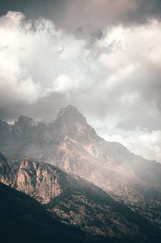 Serene landscape of a rocky mountain range enveloped by clouds and fog, creating a dramatic scene.