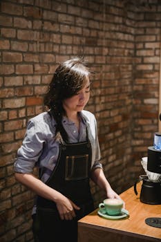 Barista prepares coffee in a cozy, rustic café setting with exposed brick walls.