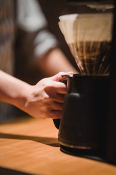 Detailed view of coffee brewing with a drip coffee maker in a cozy cafe setting.