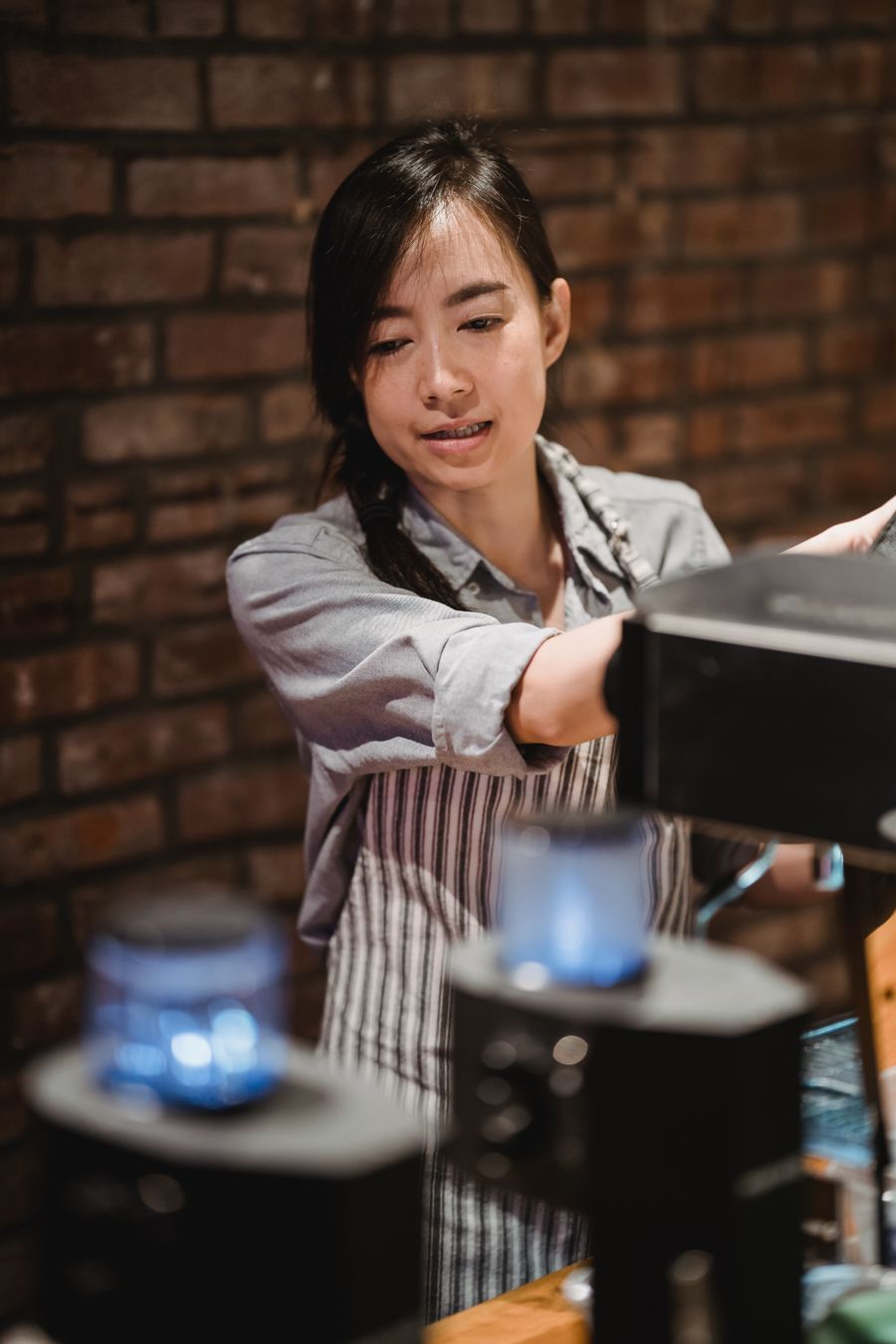 Barista con delantal preparando café en la barra de una cafetería