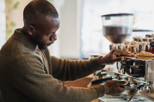 Free Focused barista brewing espresso with professional espresso machine in cozy cafe setting. Stock Photo
