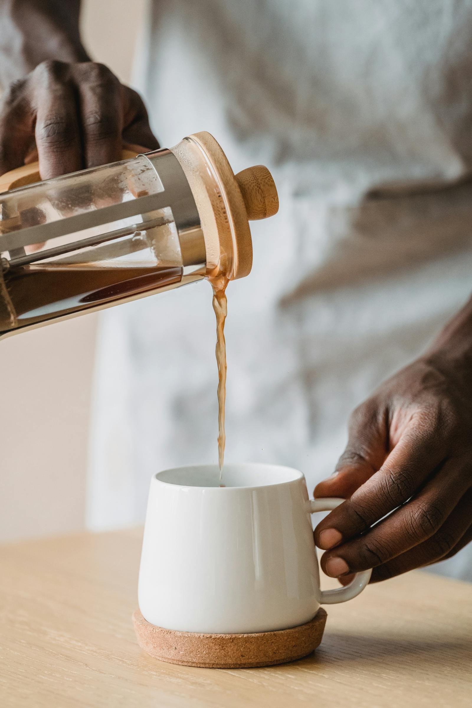 French press coffee pouring into a mug on a table