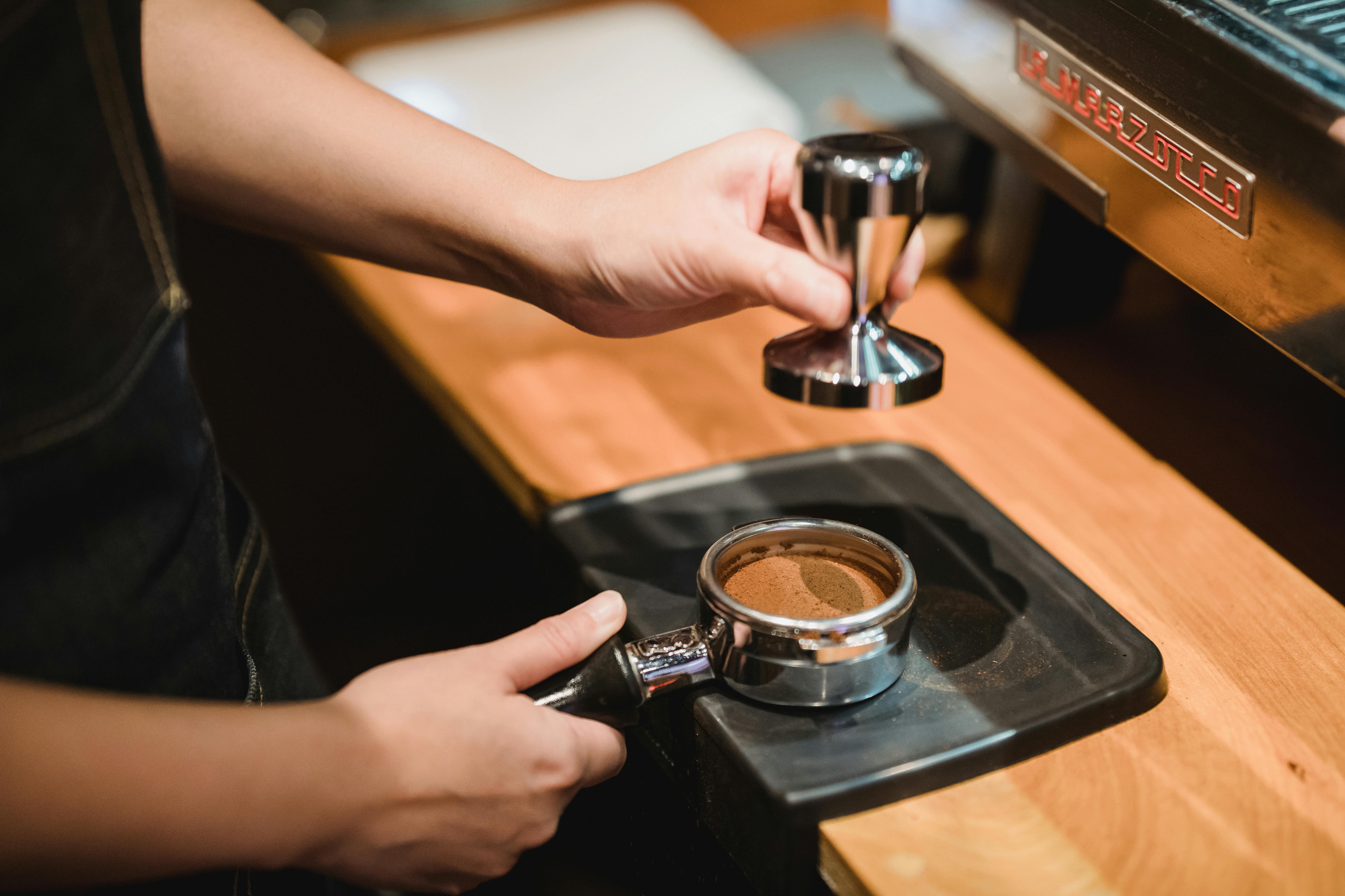 Crop anonymous man using tamper for pressing ground coffee in portafilter -  a Royalty Free Stock Photo from Photocase