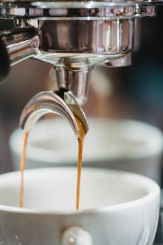 Detailed shot of espresso being dispensed into cups from a coffee machine.