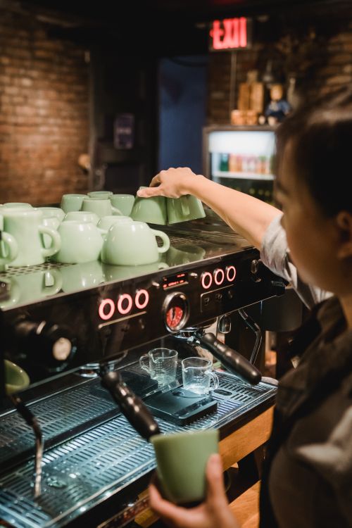 Free Barista arranging cups on espresso machine in a warm café setting. Stock Photo