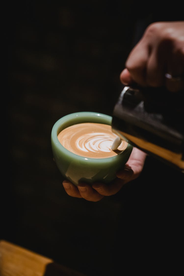 Close-up Of Person Making Wheat Latte Art With Foamed Milk 