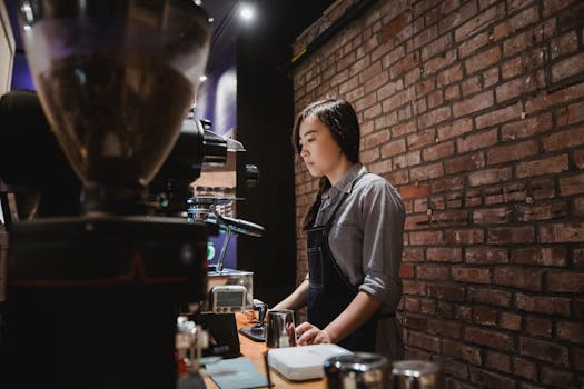 Barista preparing coffee at a café with brick wall ambiance and espresso machine.