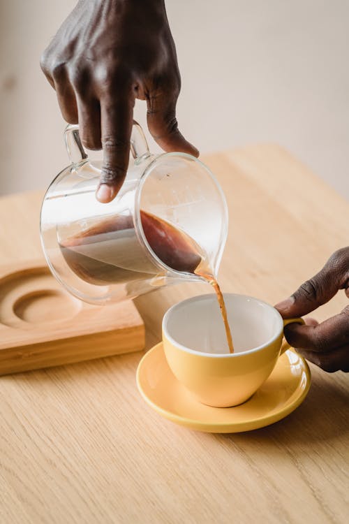 Man Pouring Coffee From a Pot into a Cup 