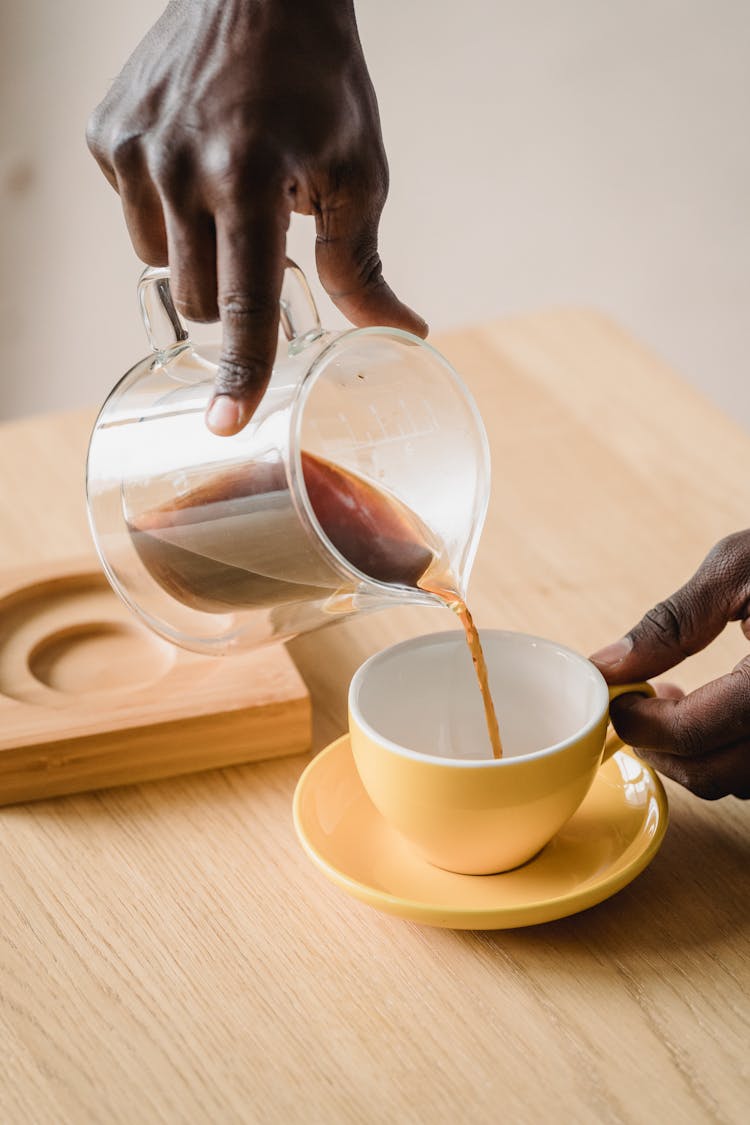 Man Pouring Coffee From A Pot Into A Cup 