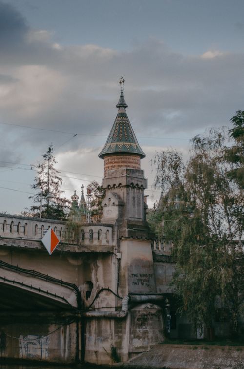Free Charming medieval tower atop a historic bridge surrounded by lush trees. Stock Photo