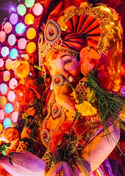 Colorful close-up of Ganesh idol with flowers and lights, celebrating Ganesh Chaturthi.