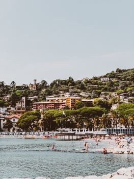 Idyllic seaside town with lush green hills and vibrant waterfront life.