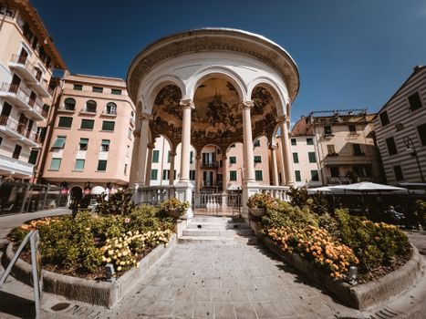 Low angle view of Chiosco della Musica, a historical monument in Rapallo, Italy, with vibrant flowers and a clear blue sky.