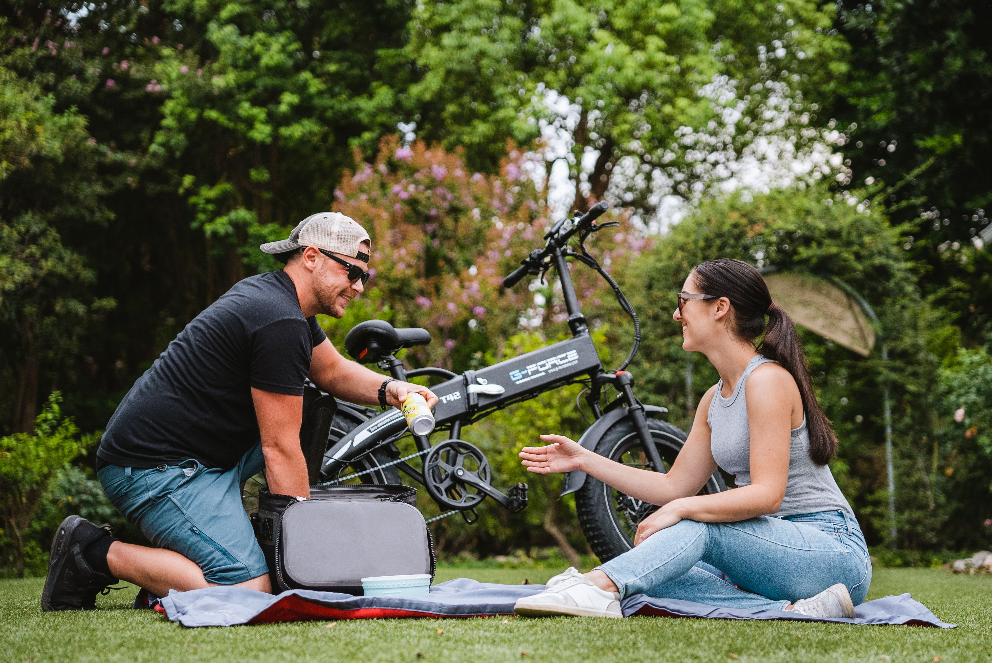 Smiling couple picnicking beside a bicycle in a lush green park