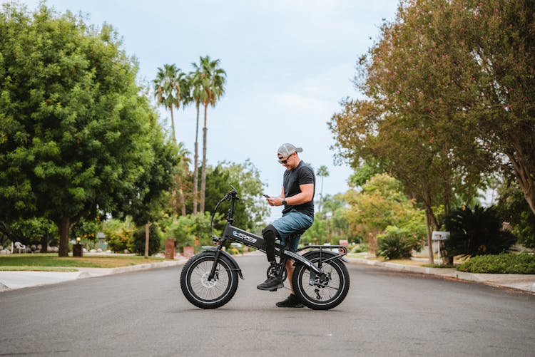 Man On A Bike In A Park Looking At Phone