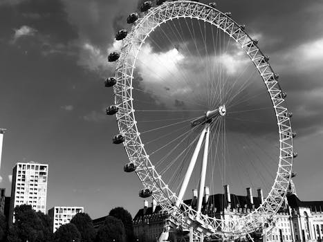 一张伦敦眼摩天轮的黑白图像，背景是多云的天空