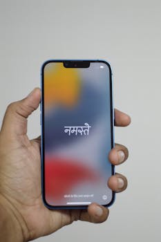 A hand holding a smartphone displaying text against a blurred background.