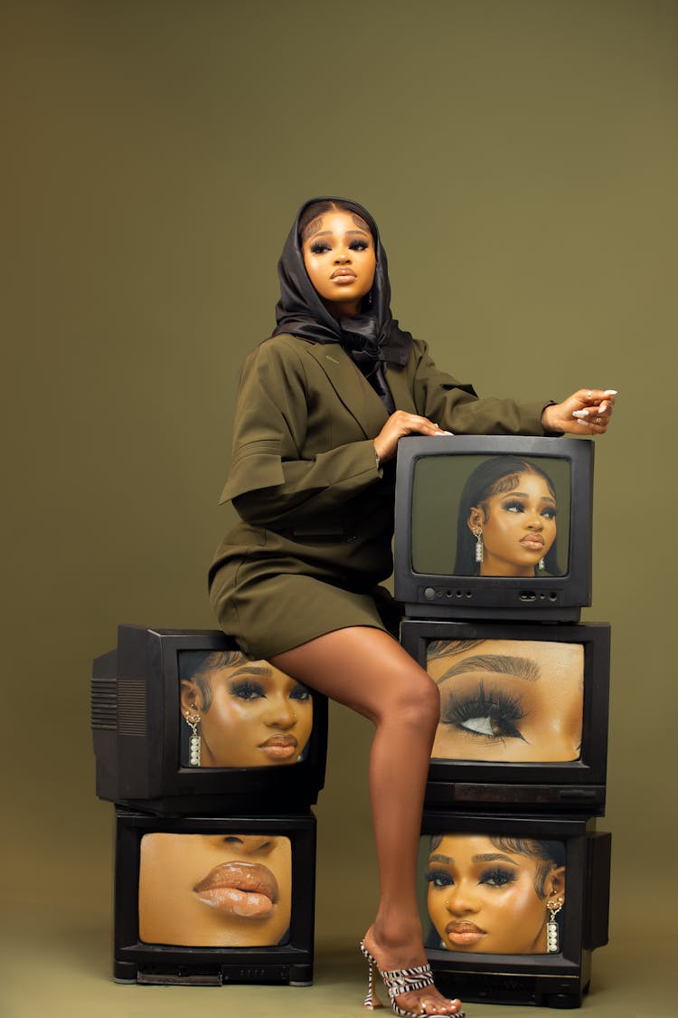 Studio Shoot Of A Woman With Television Sets Against Olive Green Background