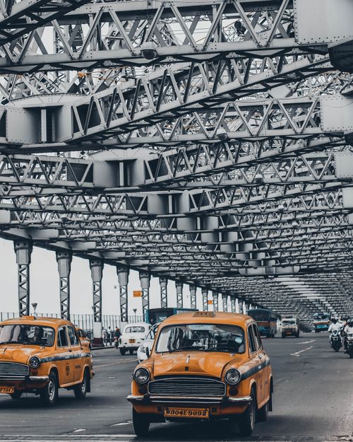 Free Yellow taxis on the bustling Howrah Bridge, showcasing Kolkata's vibrant urban life. Stock Photo