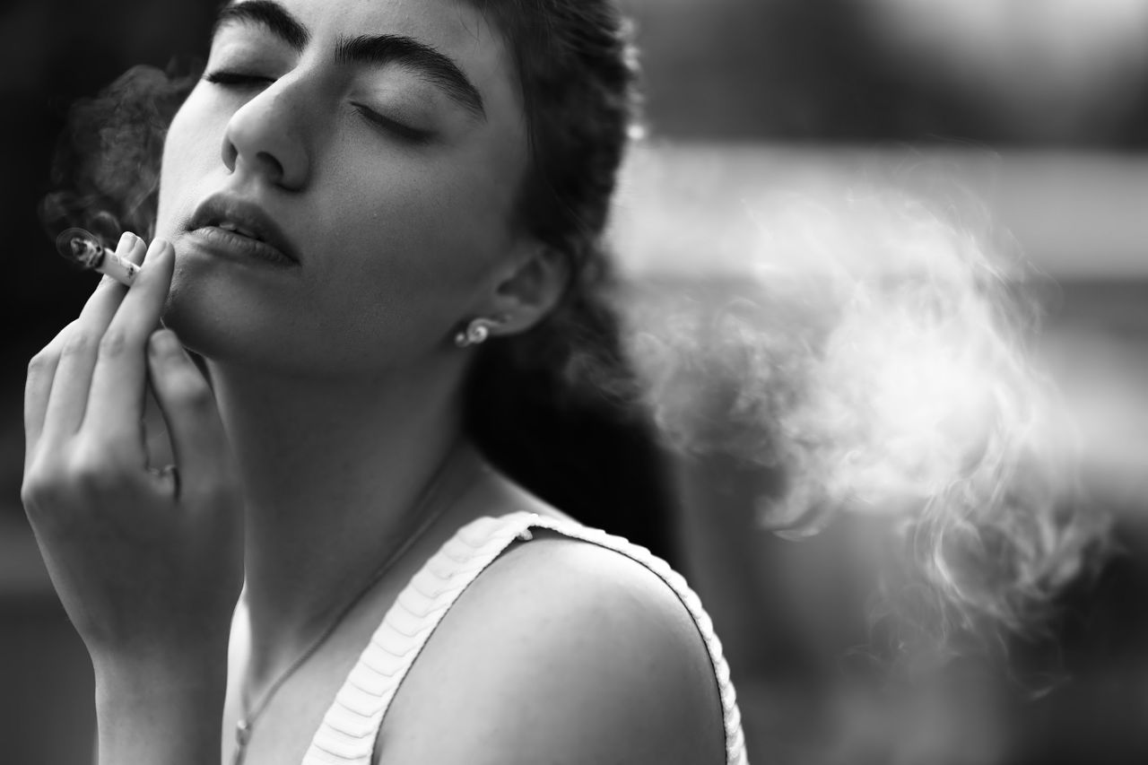 elegant black and white portrait of a woman smoking with eyes closed