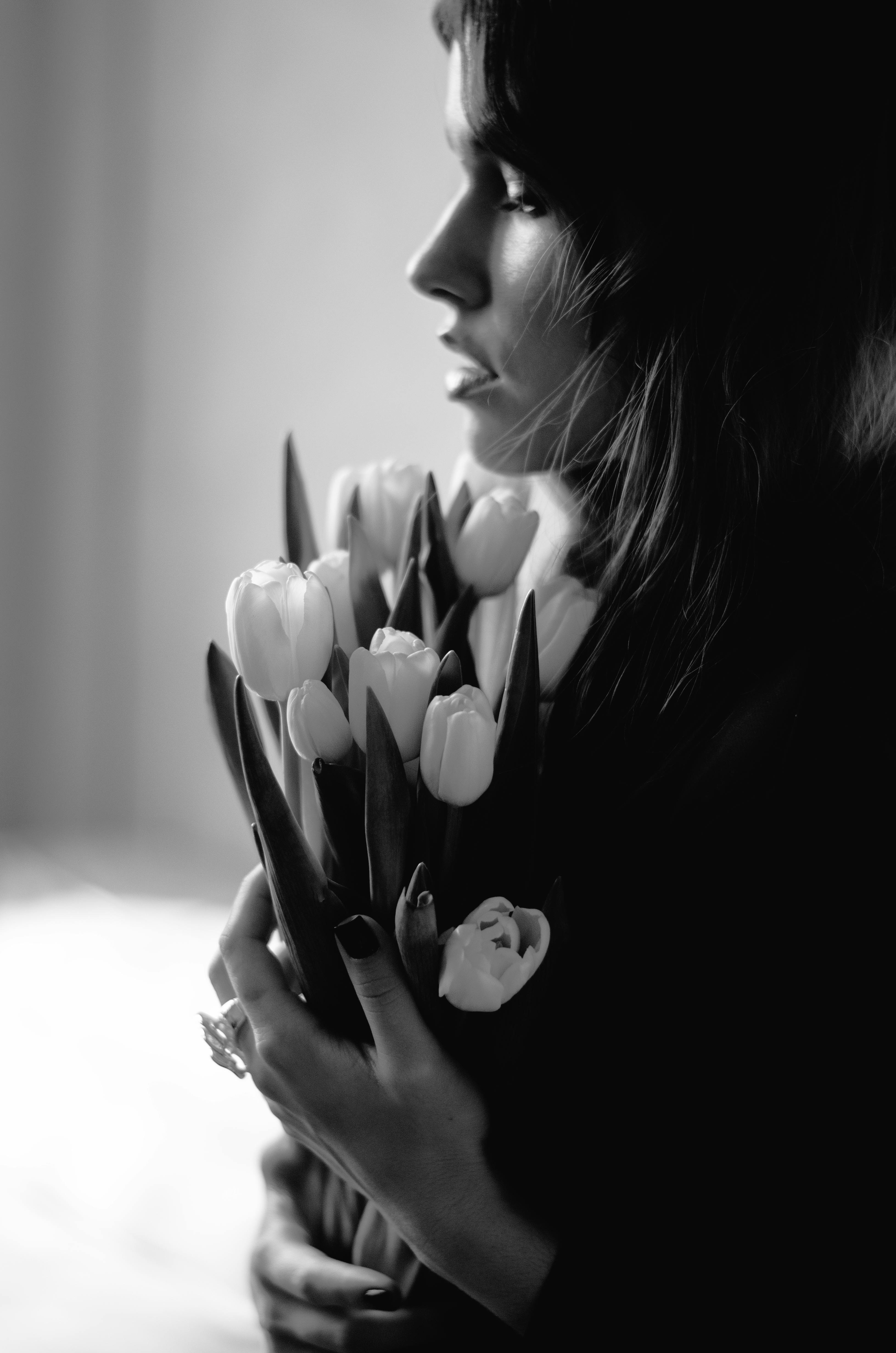 Side profile of a woman holding tulips in a stylish black and white photograph.
