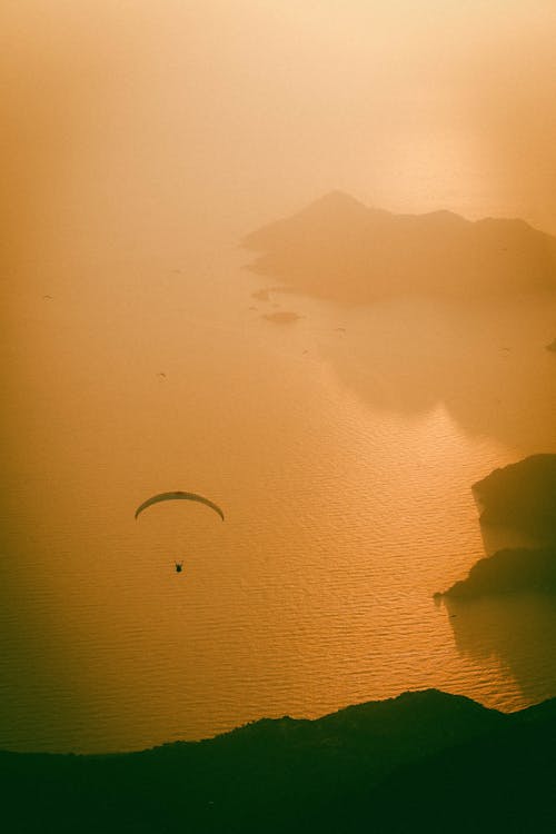 Silhouette of a Person Paragliding above Sea