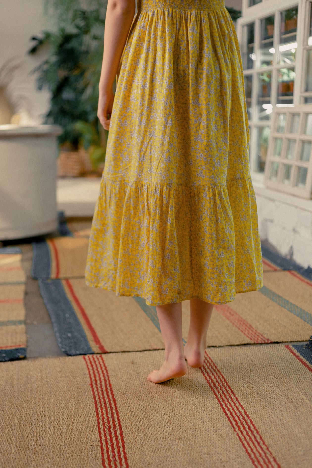Back view of a woman in a yellow floral tiered midi dress